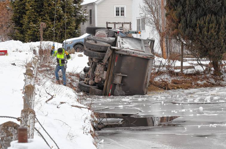 A dump truck carrying gravel lies partially submerged in Tully Pond along Tully Road in Orange on Friday morning.