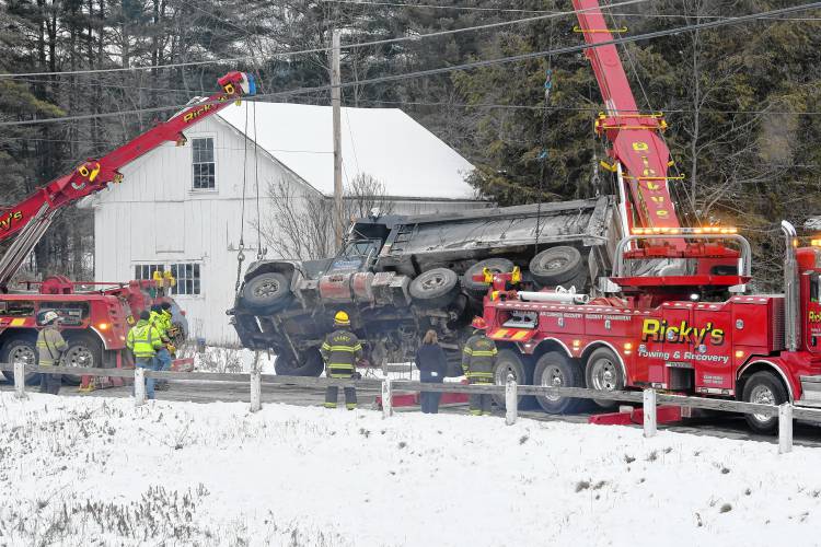 Two tow trucks from Ricky’s Towing and Recovery of Leominster hoist a dump truck out of Tully Pond along Tully Road in Orange on Friday morning. 