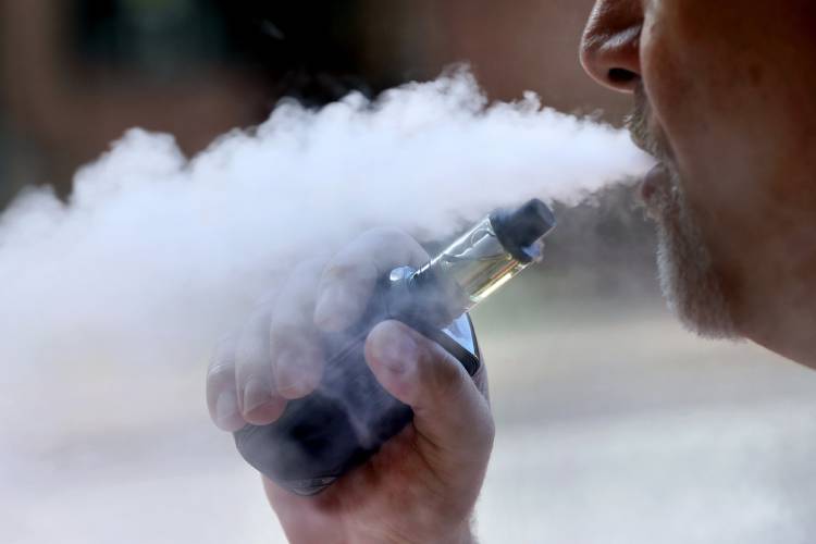 A man exhales while smoking an e-cigarette. A man exhales while smoking an e-cigarette.