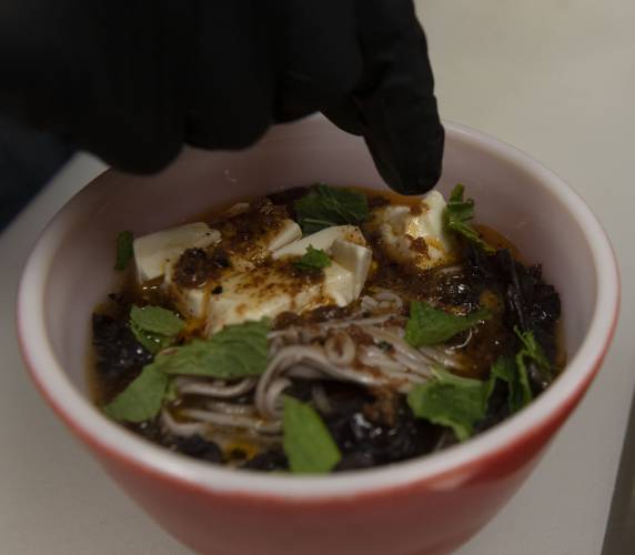 Billy McKerchie, owner of The Upper Bend Cafe, adds tofu to the soba noodle bowl.