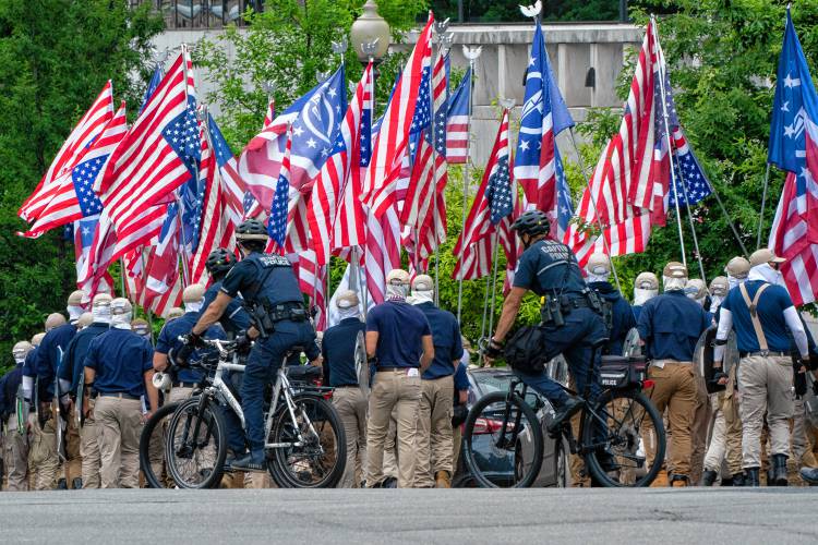 Carrying shields, covering their faces, and holding upside down U.S. flags, marchers with the white supremacist group known as the “Patriot Front,” chant the phrase “reclaim America,” while marching near the Capitol, Saturday, May 13, 2023, in Washington.