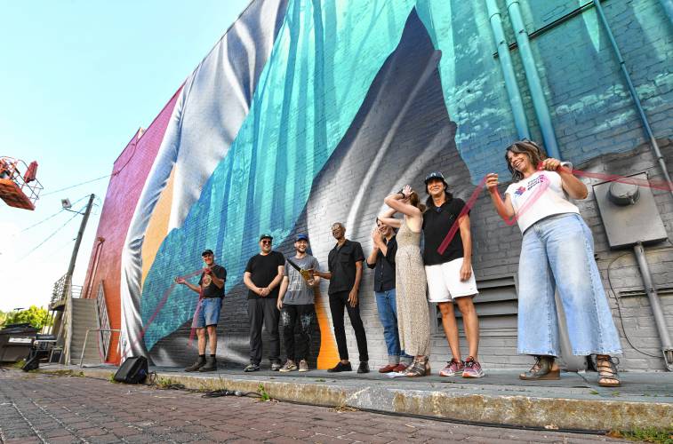 People gather in Turners Falls on Saturday afternoon for a ribbon-cutting ceremony for the mural created by Darion Fleming on the side of the Shea Theater Arts Center.