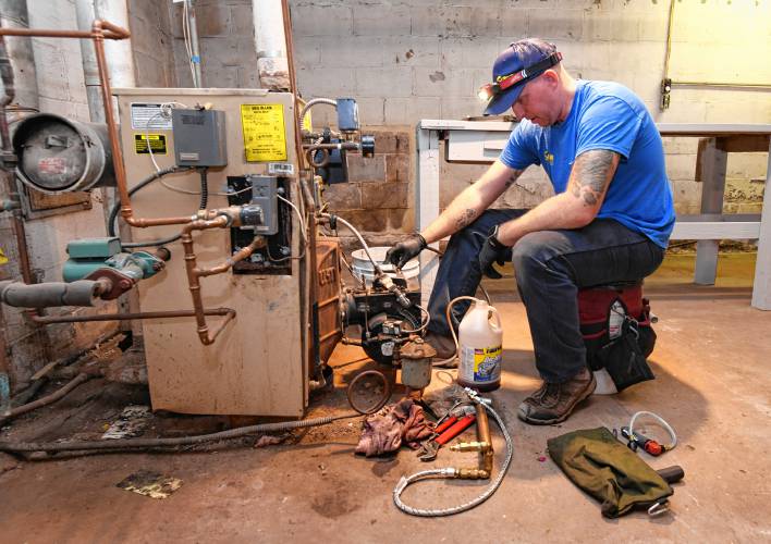 Andy Surner of Surner Heating works on an oil-burning furnace and water heater for a Montague resident. Andy Surner of Surner Heating works on an oil-burning furnace and water heater for a Montague resident.